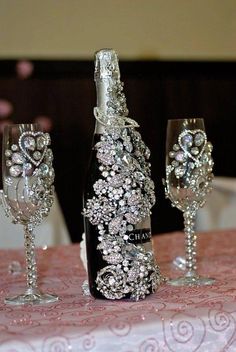 three wine glasses sitting on top of a table next to a bottle of wine and two crystal goblets