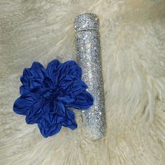 a blue flower sitting on top of a fur covered floor next to a silver vase