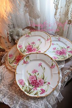 three plates with pink flowers on them are sitting on a table next to a window