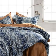 a bed with blue and brown comforters in front of a window