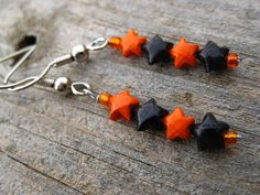 black and orange star earrings with swarong crystals on them sitting on a piece of wood