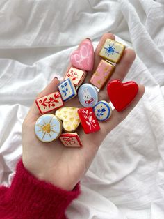 a person holding several different types of buttons in their hand on a white sheet background