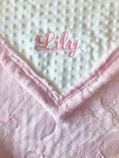 a pink blanket with the word lilly embroidered on it's side and a white dotty background