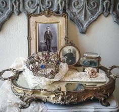 an old fashioned vanity with pictures and other items sitting on top of it, in front of a wall