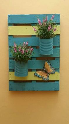 a wooden pallet with flowers and two butterflies on the side, painted yellow and blue