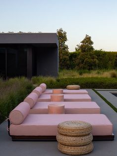 a pink couch sitting on top of a cement floor next to a lush green field