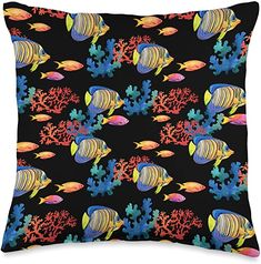 a black pillow with colorful fish and corals on the bottom, in front of an ocean background