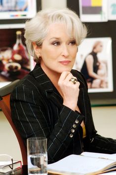 an older woman sitting at a desk with her hand on her chin and looking off to the side