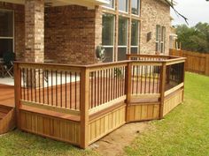 a wooden deck in front of a brick house