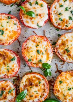 several mini pizzas with cheese and basil on top