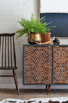 a plant is sitting on top of a dresser next to a blackboard and chair