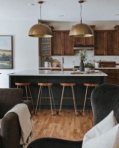 a kitchen and living room are shown in this image with wood floors, black cabinets, and bar stools