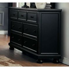 a black dresser with two vases on top of it and a mirror behind it