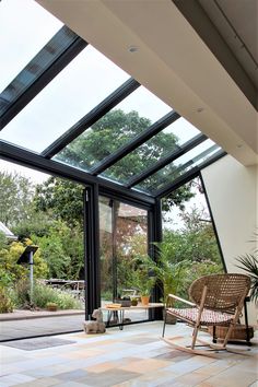 an open room with glass walls and wooden chairs on the floor, surrounded by greenery