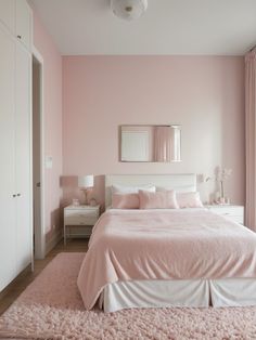 a bedroom with pink walls and white bedding in the center, along with an area rug on the floor