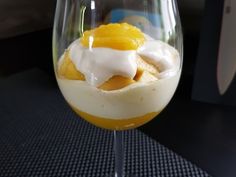 a close up of a wine glass filled with fruit and whipped cream on the side