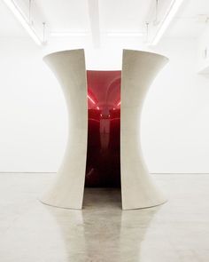 a large red vase sitting in the middle of a white room next to two tall pillars