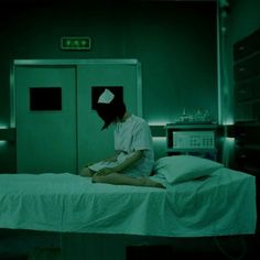 a woman sitting on top of a bed in a green lit room with an oxygen ventilator