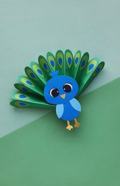 an origami peacock with blue feathers on it's tail sitting on a green surface