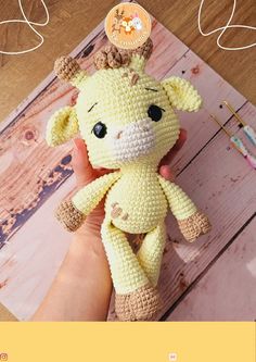 a hand holding a small stuffed animal on top of a wooden table