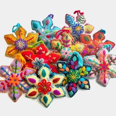 a pile of colorful felt flowers sitting on top of a white table next to each other