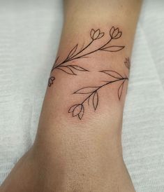 a tattoo on the foot of a woman's leg with leaves and flowers drawn on it