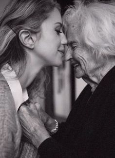 an older woman is kissing the younger woman's face in black and white photo