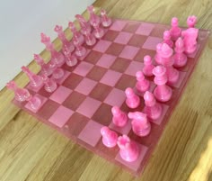 a pink plastic chess set on top of a wooden table