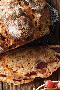 two loaves of bread sitting on top of a table next to grapes and other fruit