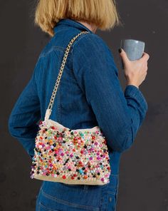 a woman holding a coffee cup in her right hand while wearing a denim jacket and jeans