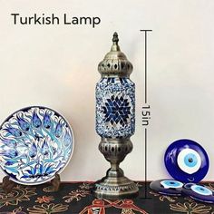 a blue and white vase sitting on top of a table next to a plate with an evil eye