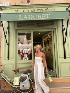 a woman in a white dress is walking out of a store