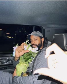 a man sitting in the back seat of a car holding flowers