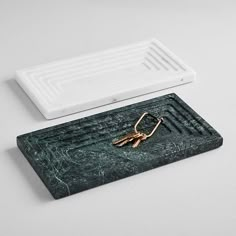 a pair of gold keys sitting on top of a green marble coaster next to a drain cover