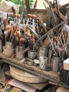 an assortment of paint brushes in tins on a table