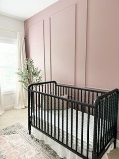 a baby crib in front of a pink wall