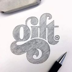 the word gift is drawn on paper next to a fountain pen and some ink pens