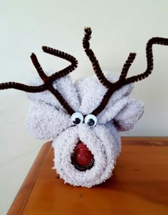 a stuffed reindeer head sitting on top of a wooden table