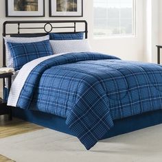 a bed with blue and white plaid comforter in a bedroom next to a window