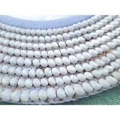 a white beaded necklace on a green and blue blanket