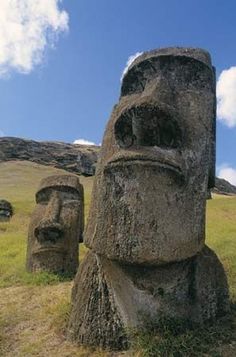 some statues in the middle of a field with mountains in the backgrouds