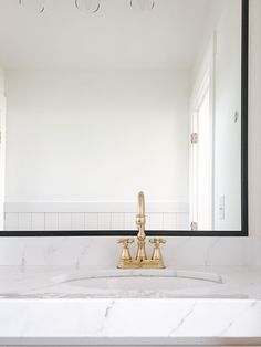 a bathroom sink with gold faucet and marble counter top