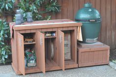 a large green egg sitting on top of a wooden table next to a bbq