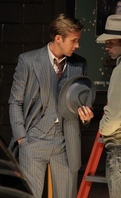 two men in suits and hats standing next to each other