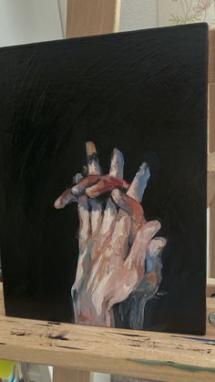 a painting of a person's hand holding something in the air on a black background