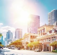 the sun shines brightly in front of some tall buildings and palm trees on a city street