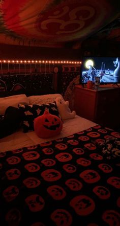 a bed with a black and red bedspread in front of a tv screen