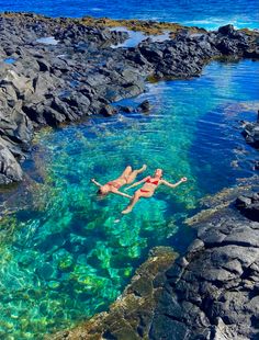 two people are swimming in the clear blue water