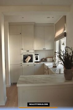 a kitchen with white cabinets and counter tops