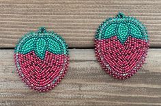 two pairs of beaded strawberry earrings sitting on top of a wooden table